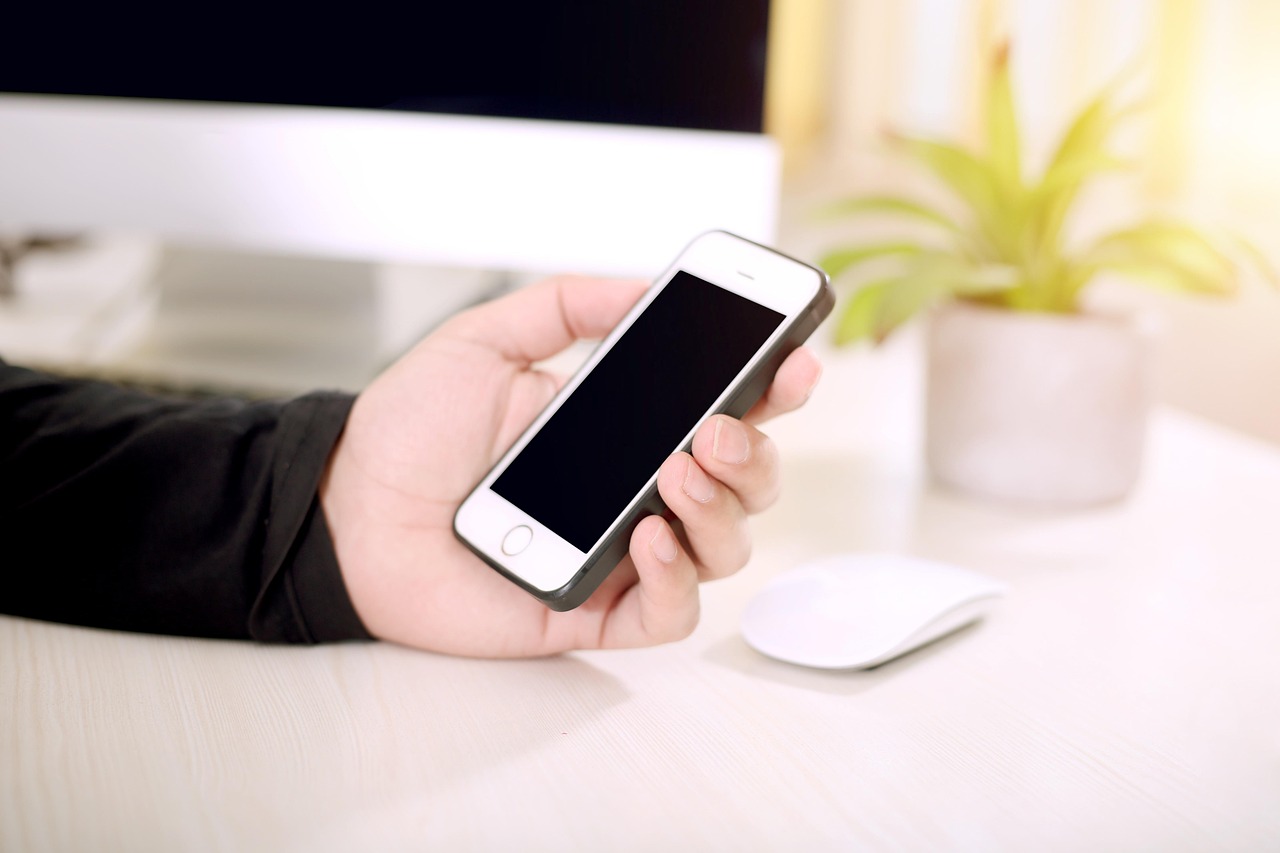 一隻手拿著iPhone放在桌上