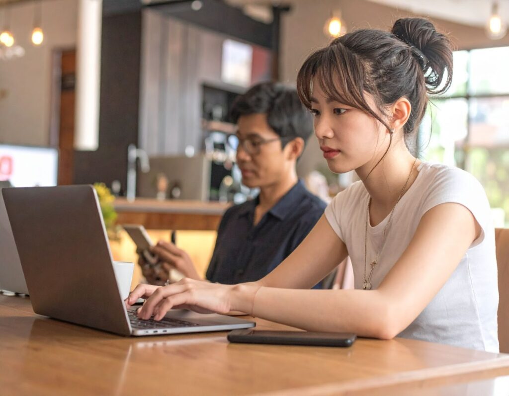 學生坐在咖啡廳使用筆電查詢二手機評價網站